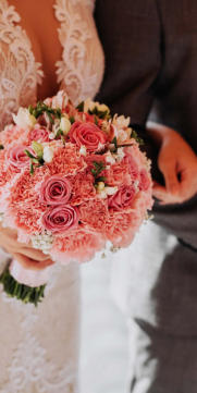 Braut mit Bräutigam, die Braut hält wunderschöne Blumen in der Hand 