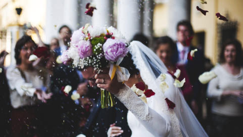 Prachtvoller Brautstrauß, bereit für den Wurf. Gäste lachen und feiern auf der fröhlichen Hochzeitsfeier 