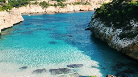 Strand in Mallorca, umgeben von Felsen und klarem Wasser