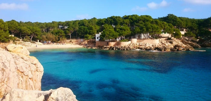 Strand in Mallorca, umgeben von Felsen und klarem Wasser sowie der Natur im Hintergrund