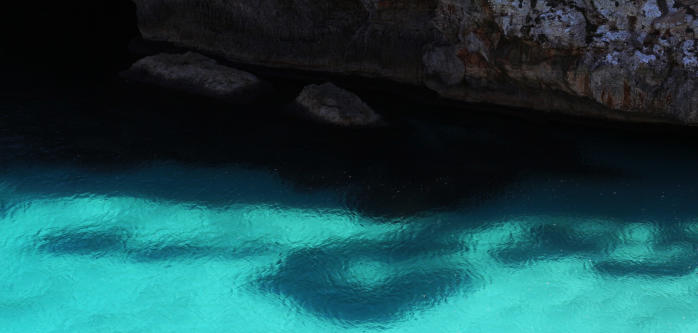 Hellblaues Meer an einer Steinwand auf Mallorca